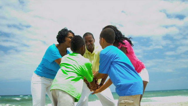Active ethnic family celebrating together successful game on beach 
