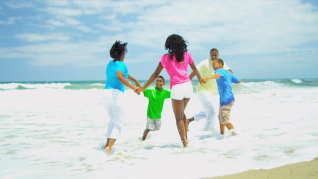 African American family have fun together on beach holding hands