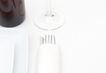 Place setting with white plates, cutlery and wine on white cloth