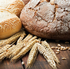 fresh bread and rolls with ears of wheat on the table