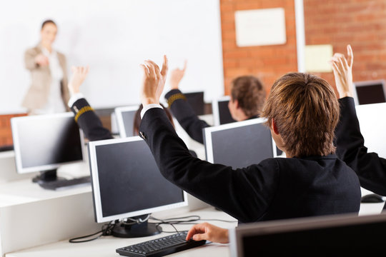 group of high school students hands up in computer class