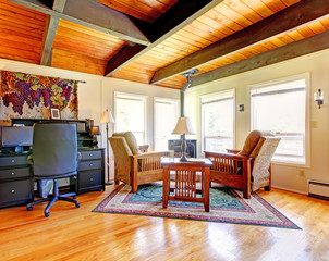 Living room with wood ceiling, computer desk and stove.