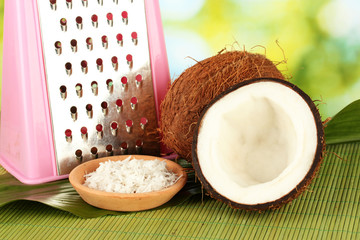 coconuts wirh pink grater on green bamboo mat close-up