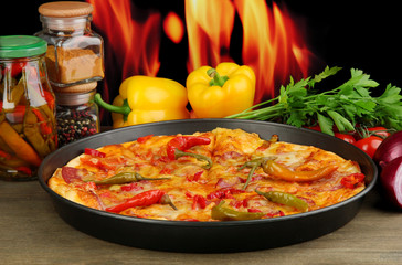 Tasty pepperoni pizza in pan with vegetables on flame