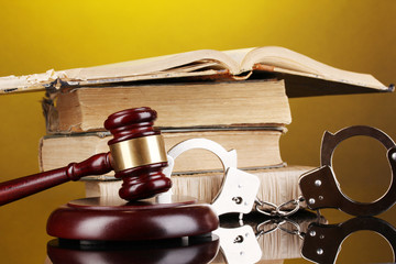Gavel, handcuffs and.book on law on yellow background