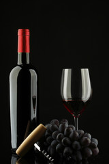 bottle with red wine and glass and grapes