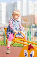 Adorable girl swing on playground near living building