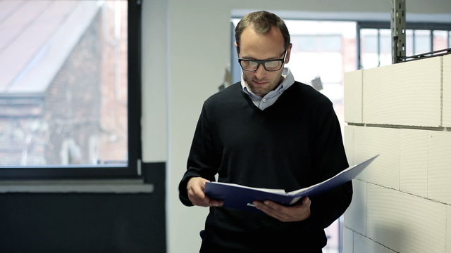 Portrait of smiling businessman with documents in the office hal