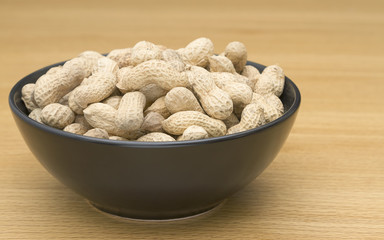 Peanuts in a black bowl on table