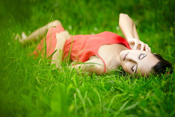 beautiful  brunette girl lying in green summer bright grass