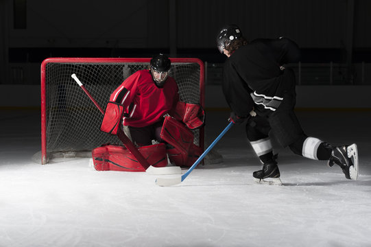 Ice hockey goalie with skaters shooting puck
