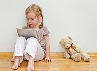 Cute little girl sitting on the floor and using tablet computer © M-Production