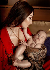 beautiful indian woman laying with baby in ethnic interior