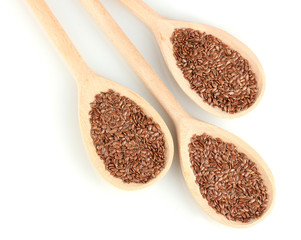 flax seeds in wooden spoons on white background close-up