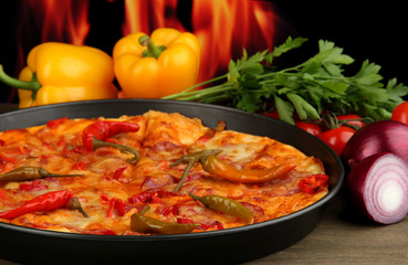 Tasty pepperoni pizza in pan with vegetables on flame