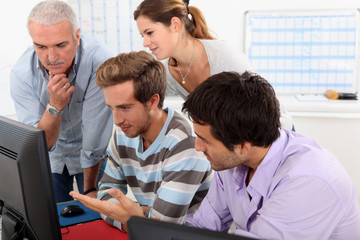Group of people sitting round a computer