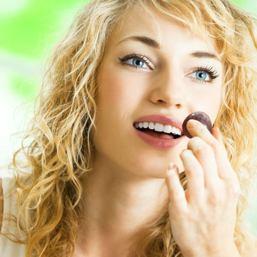Young happy woman eating grape