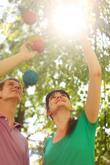 Husband, wife stretch up to decorative balls in sun