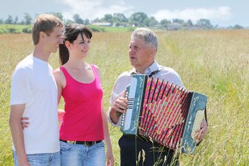 Grandfather in shirt play on accordion, sing for couple