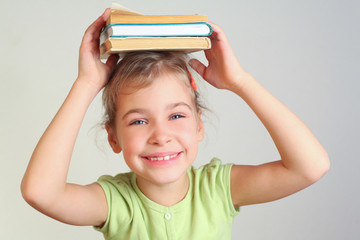 Smiling little girl hold books on head