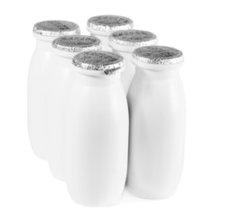 bottles with foil cap with yogurt stand on table