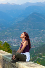 Fototapeta na wymiar Woman with eyes closed sitting on a ledge.