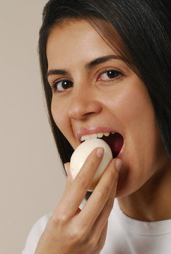 Joven mujer comiendo un huevo sancochado.
