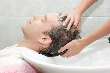 Fototapeta na wymiar blonde in a salon getting washed her hair with shampoo
