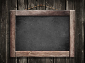 Grunge small blackboard hanging on wooden wall as a background f