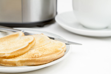 Two slices of toast with toaster and cup