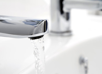 Water flowing from tap into basin