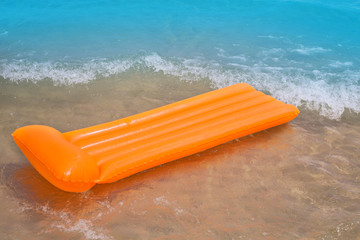 Beach shore with orange floating lounge and waves