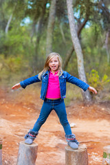 kid girl climbing tree trunks with open arms