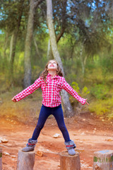 Fototapeta premium kid girl climbing tree trunks with open arms