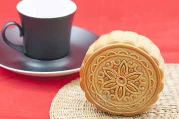 Chinese moon cake on a bamboo mat and a cup of tea.