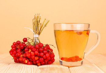 tea with red viburnum on table on beige background