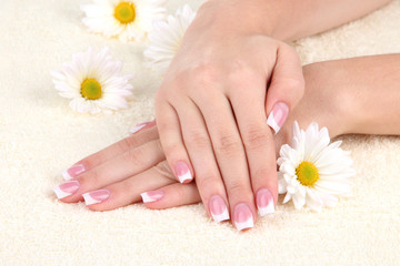 Fototapeta premium Woman hands with french manicure and flowers on towel