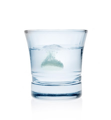 Effervescent tablet splashing into glass full of water