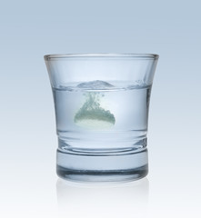 Effervescent tablet splashing into glass full of water