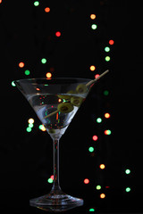 Martini glass and olives on dark bright background