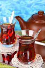 glass of Turkish tea and kettle on color background