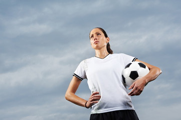 Fußballerin mit Fußball vor Himmel