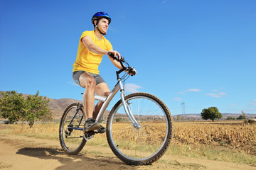 Fototapeta na wymiar Młody mężczyzna w żółtej koszuli na rowerze