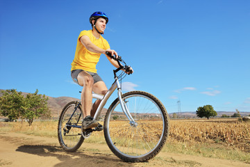 Fototapeta premium A young male in yellow shirt riding a bike