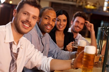 Happy young people sitting in pub, drinking beer