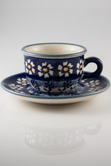 cup and saucer with daisies on a white