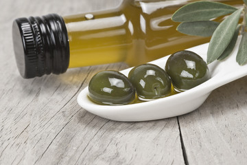 Aceite de oliva y aceitunas verdes sobre fondo de madera