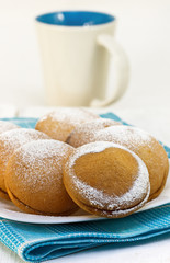 biscuits on a white plate and mug of milk on a white wooden back