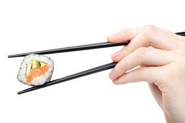Hand holding fresh maki sushi roll with black chopsticks