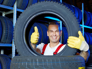 Funny car mechanic stores winter tires and shows thumb up
